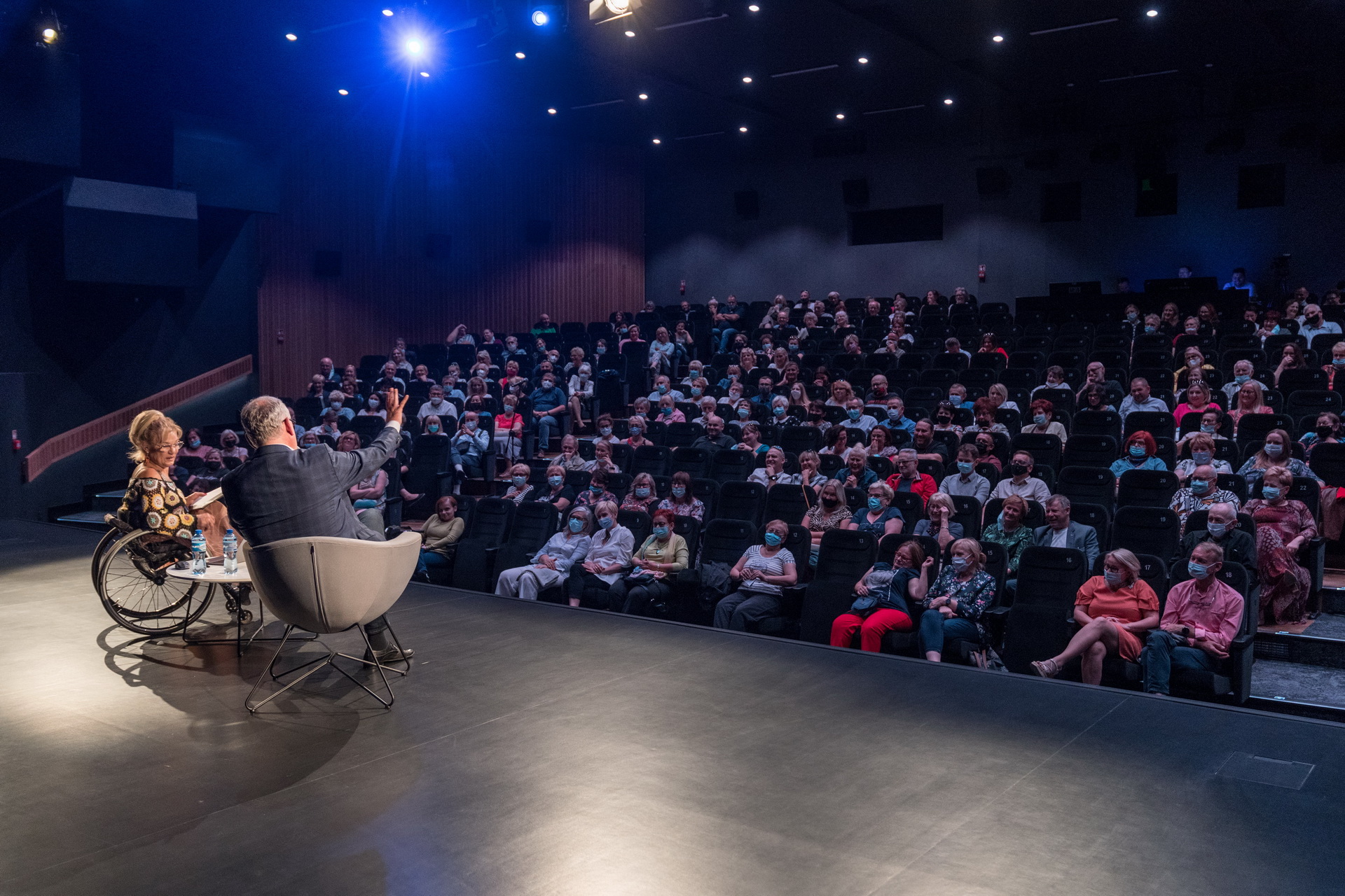 Na scenie Domu Kultury Oskard siedzi Artur Andrus z dziennikarką Iwoną Krzyżak. Na widowni siedzi dużo osób 